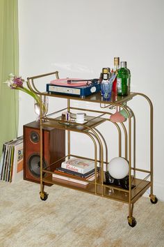 a gold metal shelf with books and drinks on it