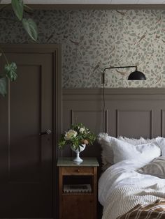 a bed with white sheets and pillows in a bedroom next to a wallpapered wall