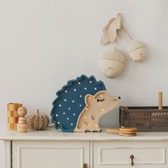 a toy hedge sitting on top of a white dresser next to a wall mounted light