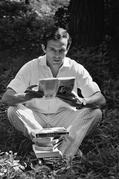 a man sitting in the grass reading a book