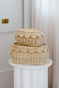 two wicker baskets stacked on top of each other in front of a white door