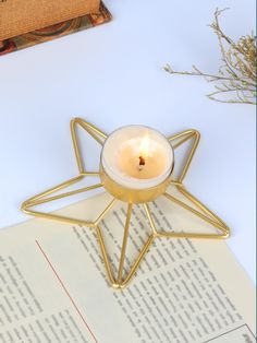 a lit candle sitting on top of an open book next to a star shaped candle holder