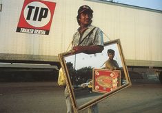 a man is holding up a mirror with the reflection of himself in it