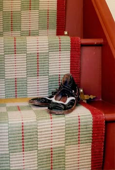 a pair of shoes sitting on top of a set of stairs next to a carpeted stair case