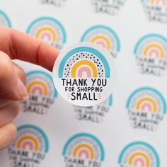 a person holding up a sticker with the words thank you for shopping small on it