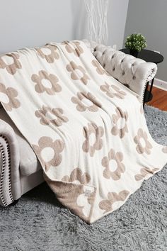 a bed covered in a white and brown flowered blanket on top of a gray rug