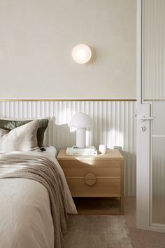 a bedroom with a bed, night stand and two lamps on the side of the wall