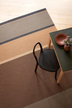 a black chair sitting on top of a rug next to a table