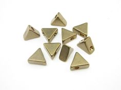 brass plated triangle shaped beads on white background