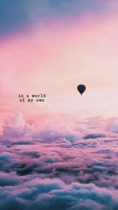 a hot air balloon flying in the sky above clouds with words written on it that says, in a world at my own