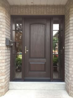 a brown front door with two sidelights and brick pillars on the outside of it