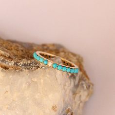 a turquoise ring sitting on top of a rock