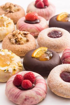 a bunch of doughnuts with different toppings on top of them and some raspberries in the middle