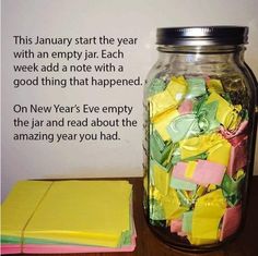 a jar filled with lots of yellow and green paper next to a notepad on top of a wooden table