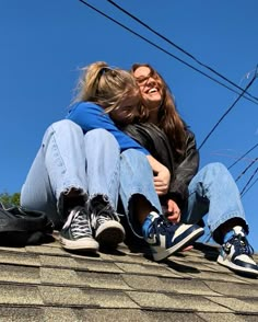 two people sitting on top of a roof hugging