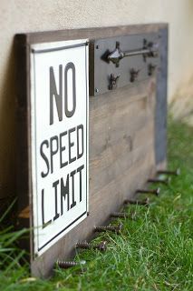 a no speed limit sign in the grass next to a building with an arrow on it