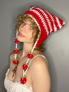 a woman wearing a red and white crocheted hat with cherries on it