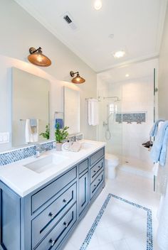 a white bathroom with blue accents and tile flooring, along with a walk in shower