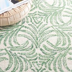 a green and white rug on the floor next to a basket with a magazine in it