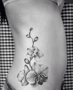 a black and white photo of a woman's stomach with an orchid tattoo on it