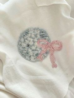 a close up of a white shirt with a pink bow on the front and an embroidered design on the back