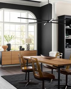 a modern dining room with black walls and wooden furniture, along with an area rug on the floor