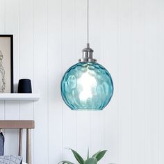 a blue glass light hanging from a ceiling in a room with white walls and wood flooring