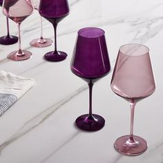 three wine glasses sitting on top of a white counter next to towels and napkins