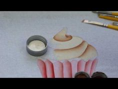 a cupcake with icing sitting on top of it next to some paint brushes