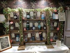 a table topped with lots of bottles of alcohol next to a white table cloth covered table