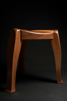 a wooden stool sitting on top of a black floor