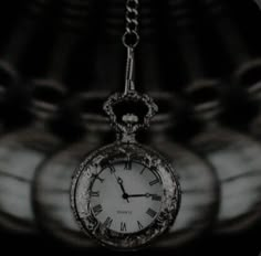 a black and white photo of an old pocket watch with chains hanging from it's sides