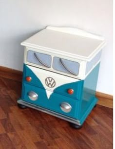 a small blue and white toy bus sitting on top of a hard wood floor next to a wall