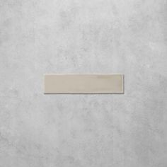 a white square tile on a gray wall with a light colored border in the middle