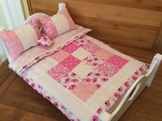 a pink and white quilted bed with pillows