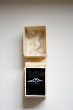 an engagement ring in a box on top of a white surface with the lid open