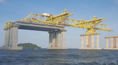 two large yellow cranes sitting on top of a bridge over water