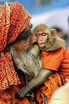 a man with a monkey on his shoulder kissing him in the face, while people look on