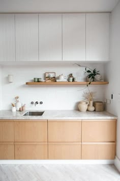 a kitchen with wooden cabinets and white counter tops, along with shelves above the sink