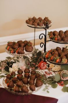 chocolate covered strawberries are arranged on three tiered trays, along with flowers and greenery