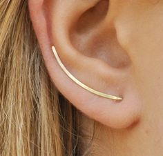 a woman's ear is shown with two thin bar earrings