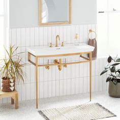 a bathroom with a sink and mirror next to a potted plant on the floor