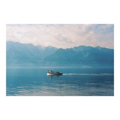 a small boat is out on the water with mountains in the backgrouds