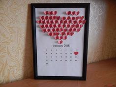 a framed calendar with hearts pinned to it