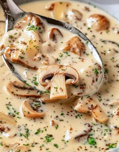 a spoon full of creamy soup with mushrooms and parmesan cheese on top, ready to be eaten