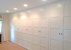 an empty room with white closets and carpeted flooring in front of a window