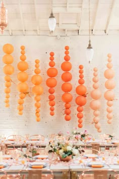 the tables are set up with orange paper lanterns hanging from the ceiling and flowers in vases