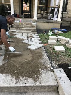 a man is shoveling dirt in front of a house with steps leading up to it