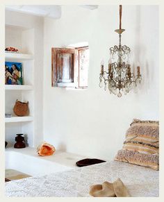 a bedroom with white walls and a chandelier hanging from the ceiling