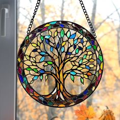 a stained glass window with a tree in the center and leaves hanging from it's chain